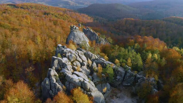 Aerial photo drone copter beautiful autumn beech forest and ancient rocks of Dovbush in Bubnishche Carpathians Ukraine, pagan temple and caves of a Christian monastery, tourist famous place