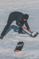 A Caucasian man shoveling snow at a ski resort