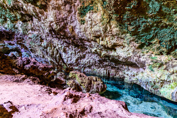 Obraz premium Stalactites and stalagmites in a Kuza cave at Zanzibar, Tanzania. Natural pool with crystal clear water