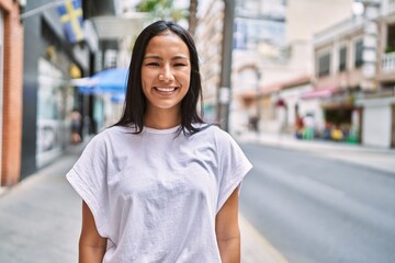 Young latin girl smiling happy standing at the city.