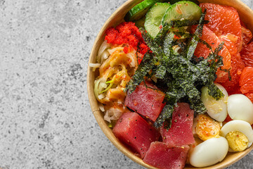 Tuna poke bowl salad in paper package for take away or food delivery on gray background. Top view. close up