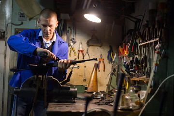 Gunsmith with Kalashnikov assault rifle in a weapons workshop