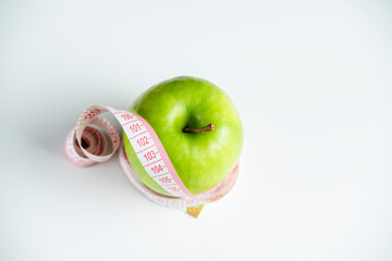 a whole green apple on a white background with a meter (measuring tape)