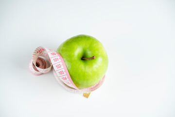 a whole green apple on a white background with a meter (measuring tape)