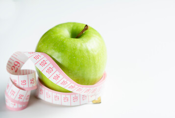 a whole green apple on a white background with a meter (measuring tape)