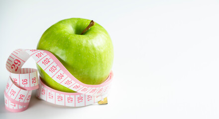 a whole green apple on a white background with a meter (measuring tape)