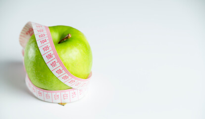 a whole green apple on a white background with a meter (measuring tape)