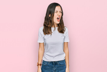 Young beautiful woman wearing casual white t shirt angry and mad screaming frustrated and furious, shouting with anger. rage and aggressive concept.