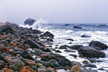 Stormy and cloudy day seascape with colorful rolling stones on the Molen beach .UNESCO Global Geopark near Larvik, Vestfold County, Norway