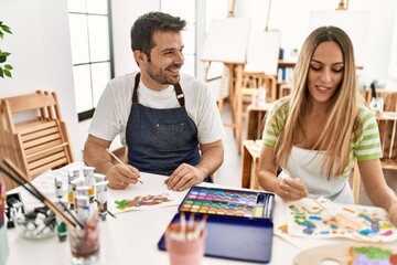 Fototapeta premium Two students smiling happy painting sitting on the table at art school.