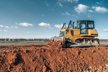 Crawler bulldozer working on construction site or quarry. Mining machinery moving clay, smoothing gravel surface for new road. Earthmoving, excavations, digging on soils. - obrazy, fototapety, plakaty