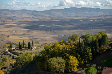 Aerial view on hills of Val d'Orcia near Castiglione d'Orcia, Tuscany, Italy. Tuscan landscape with cypress trees, vineyards, forests and ploughed fields in autumn.