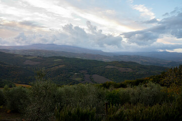 View on hills of Val d'Orcia near Bagno Vignoni, Tuscany, Italy. Tuscan landscape with cypress trees, vineyards, forests and ploughed fields in autumn.