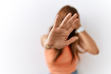Hispanic woman with bang hairstyle standing over isolated background covering eyes with hands and doing stop gesture with sad and fear expression. embarrassed and negative concept.