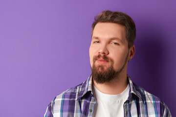 Fototapeta premium Happy bearded man in shirt smiling looking at camera on purple background. Young handsome stylish guy