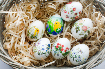 Easter eggs decorated with flowers in wicker wooden basket with shavings close up. Happy Easter