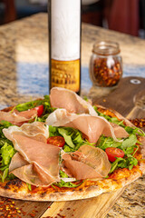 Fresh Pizza Topped with Arugula, Tomatoes and Prosciutto and Drizzled with Olive Oil