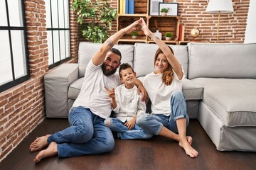 Family of three doing house shape with arms smiling happy pointing with hand and finger to the side