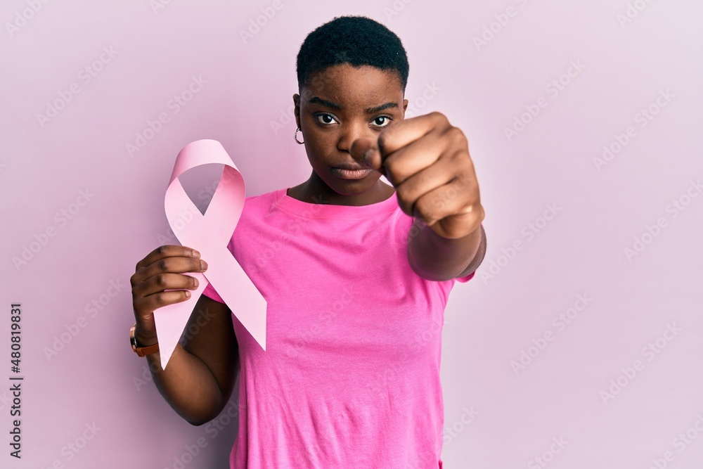 Poster young african american woman holding pink cancer ribbon annoyed and frustrated shouting with anger, 