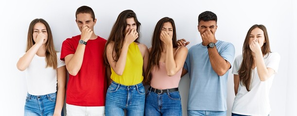 Group of people wearing casual clothes standing over isolated background smelling something stinky...