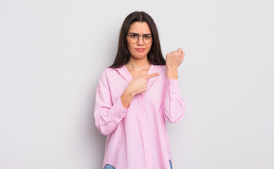 pretty young woman looking impatient and angry, pointing at watch, asking for punctuality, wants to...