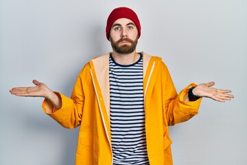 Caucasian man with beard wearing yellow raincoat smiling showing both hands open palms, presenting and advertising comparison and balance