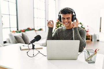 Handsome hispanic man recording podcast smiling happy pointing with hand and finger to the side