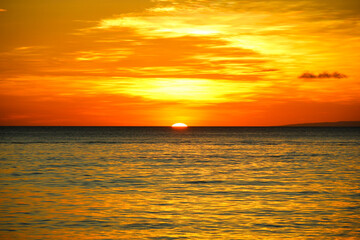 Sun going down on horizon at calm sea in Boracay island, Philippines. Perfect sunset under orange sky