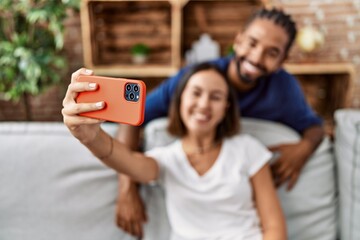 Man and woman couple smiling confident make selfie by the smartphone at home