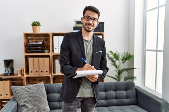 Young hispanic man having psychology session writing on checklist at clinic