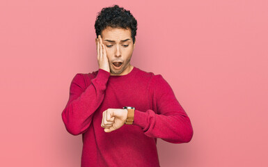 Young handsome man wearing casual clothes looking at the watch time worried, afraid of getting late