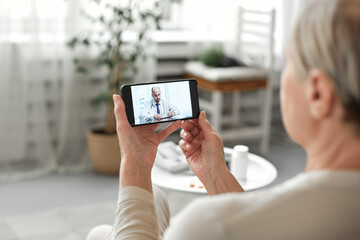 Online medicine. An old woman is talking on a video with doctor. Remote consultation of the doctor by phone.