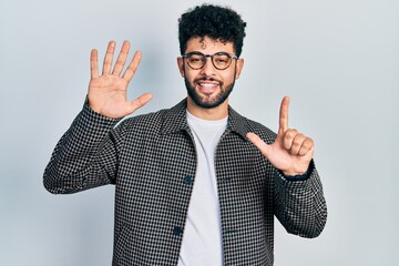 Young arab man with beard wearing glasses showing and pointing up with fingers number seven while smiling confident and happy.
