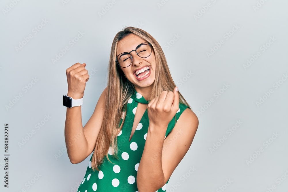 Sticker beautiful hispanic woman wearing elegant shirt and glasses very happy and excited doing winner gestu