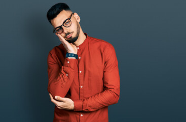 Young hispanic man with beard wearing business shirt and glasses thinking looking tired and bored...