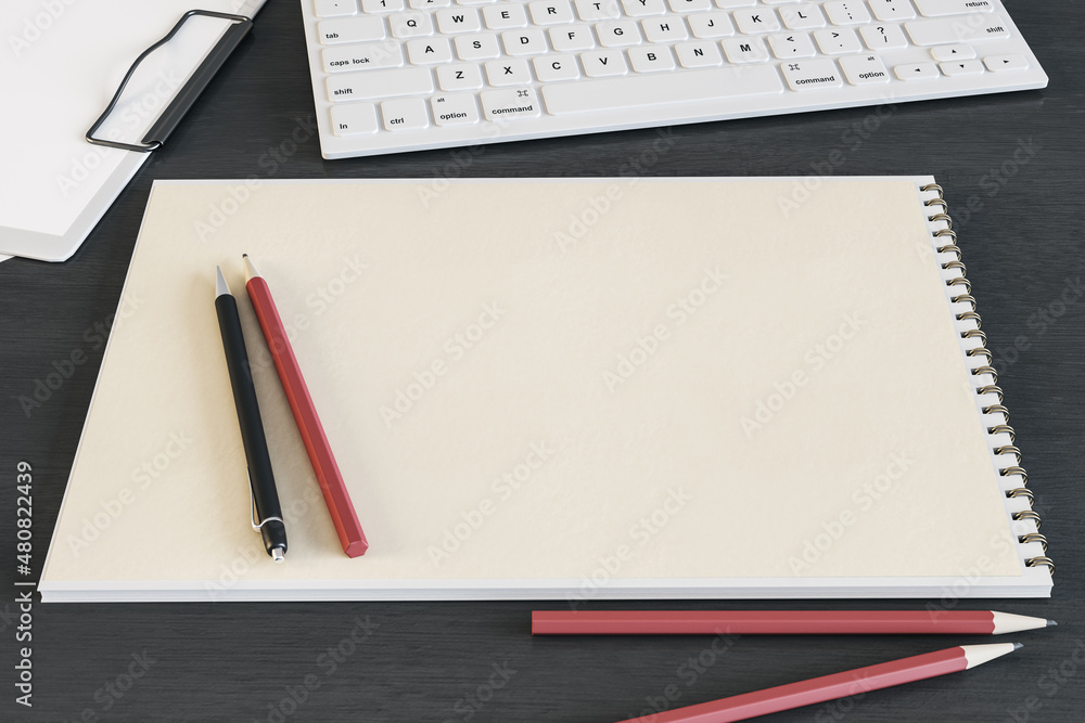 Poster top view of clean spiral notepad on dark wooden desktop with keyboard and pencils. drawing, workplac
