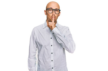 Bald man with beard wearing business shirt and glasses asking to be quiet with finger on lips. silence and secret concept.
