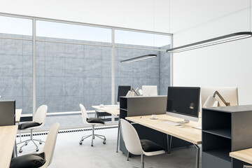 Clean coworking office interior with empty computer monitors on wooden desks, equipment, furniture and panoramic windows with daylight. 3D Rendering.