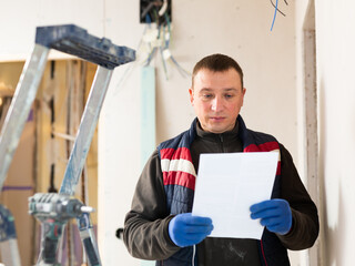 Fototapeta na wymiar Professional builder standing at indoors building site, reading document