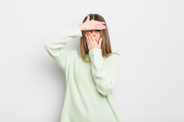 pretty young woman covering face with both hands saying no to the camera! refusing pictures or...