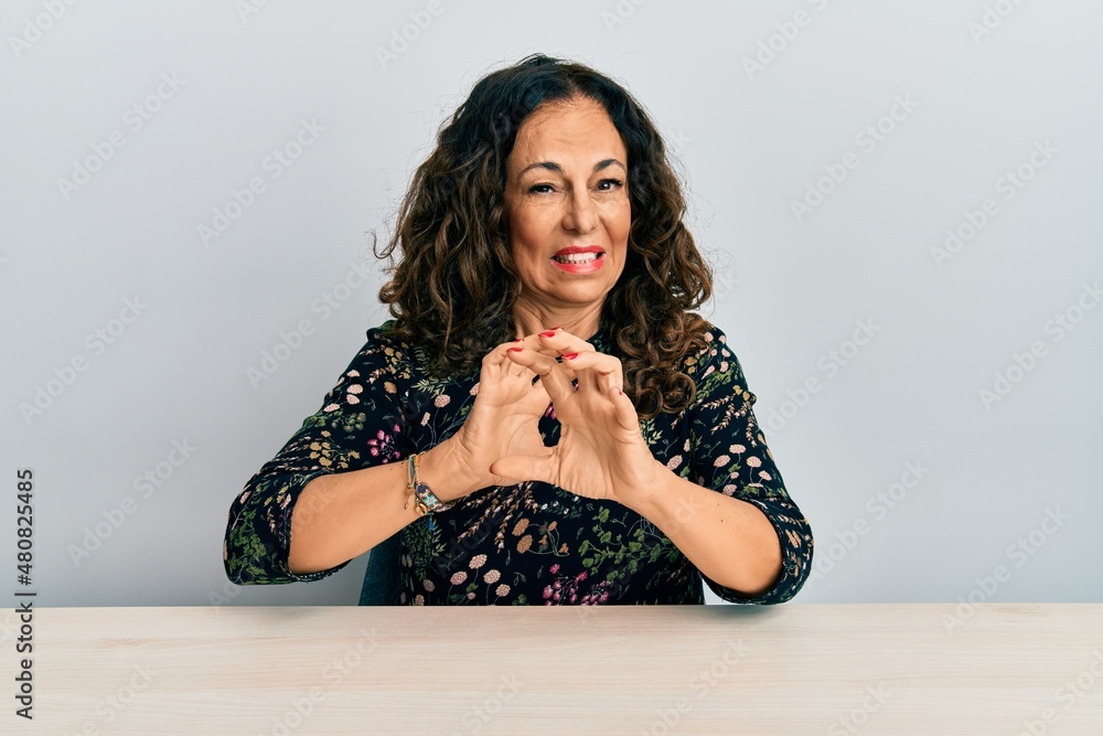 Poster beautiful middle age woman wearing casual clothes sitting on the table disgusted expression, displea