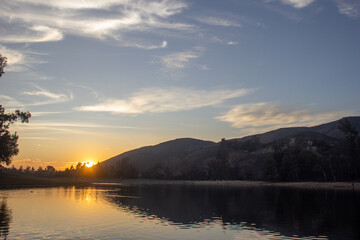 A Quiet Colorful Sunset over a Lake in Yucaipa Regional Park, California, with the Sun Reflecting off of the Rippled Water Surface