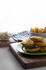 Plate with hot patacones on a table with white background. Copy space.