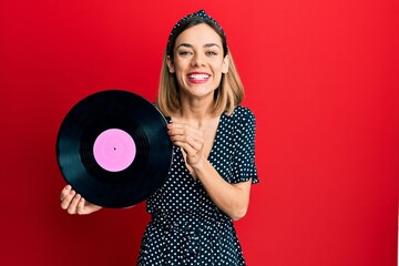 Young caucasian blonde woman holding vinyl disc smiling and laughing hard out loud because funny...