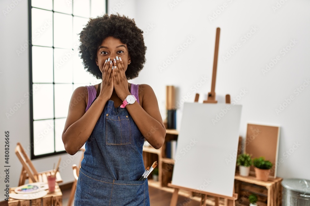 Sticker Young african american woman with afro hair at art studio laughing and embarrassed giggle covering mouth with hands, gossip and scandal concept