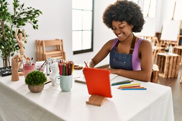 Young african american woman smiling confident looking touchpad drawing at art studio
