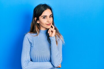 Young hispanic girl wearing casual clothes looking confident at the camera with smile with crossed arms and hand raised on chin. thinking positive.