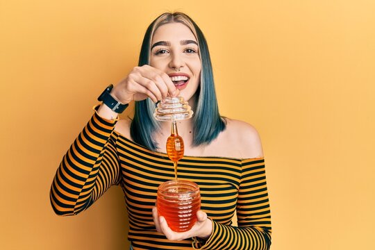 Young modern girl holding honey smiling and laughing hard out loud because funny crazy joke.
