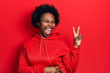 Young african american woman wearing casual sweatshirt smiling with happy face winking at the...