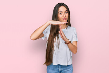 Young hispanic girl wearing casual white t shirt doing time out gesture with hands, frustrated and...